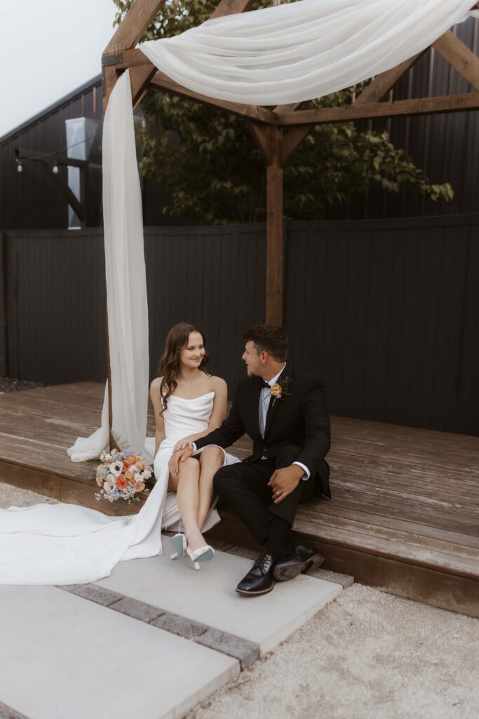 Bride and groom sharing a romantic moment outside Industrial Grove, surrounded by lush greenery and sleek modern architecture