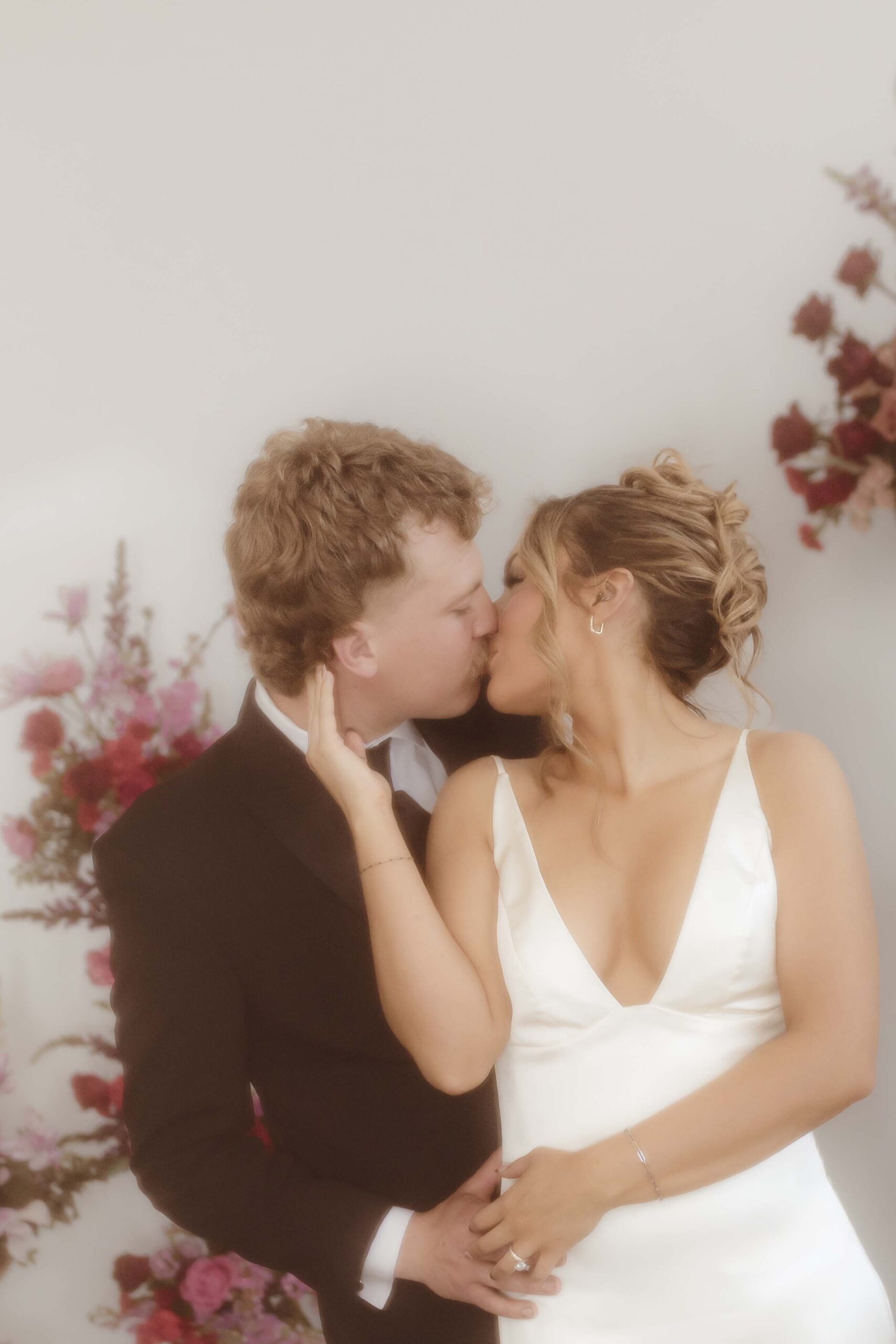 Bride and groom kissing among stunning florals during their Southwest Missouri wedding reception.