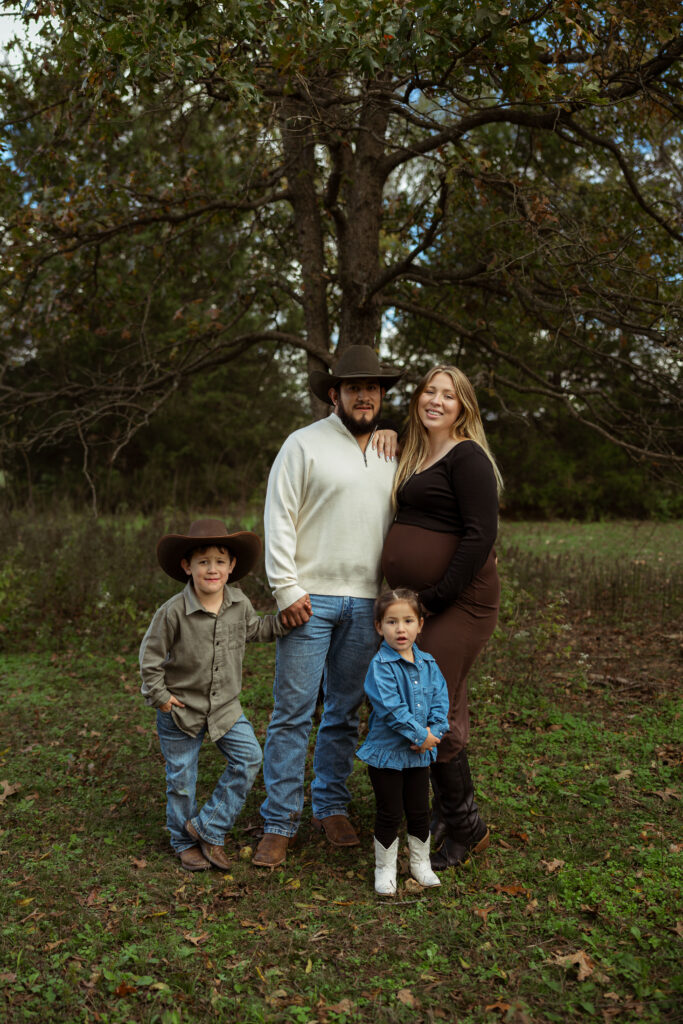 Family celebrating their upcoming baby during a fall maternity session outdoors in Missouri with warm autumn colors and western-inspired styling