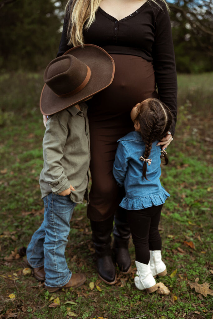Family celebrating their upcoming baby during a fall maternity session outdoors in Missouri with warm autumn colors and western-inspired styling