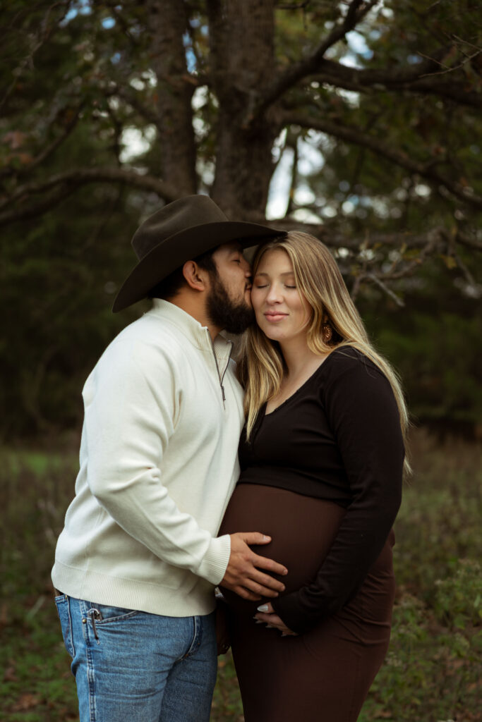 Family celebrating their upcoming baby during a fall maternity session outdoors in Missouri with warm autumn colors and western-inspired styling