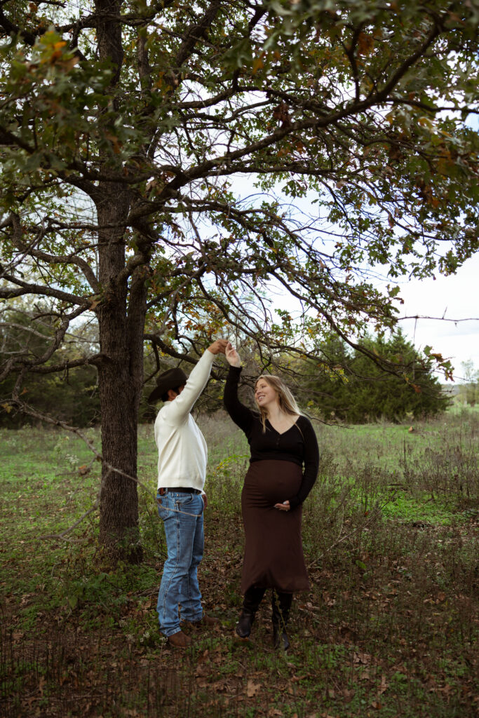 Family celebrating their upcoming baby during a fall maternity session outdoors in Missouri with warm autumn colors and western-inspired styling