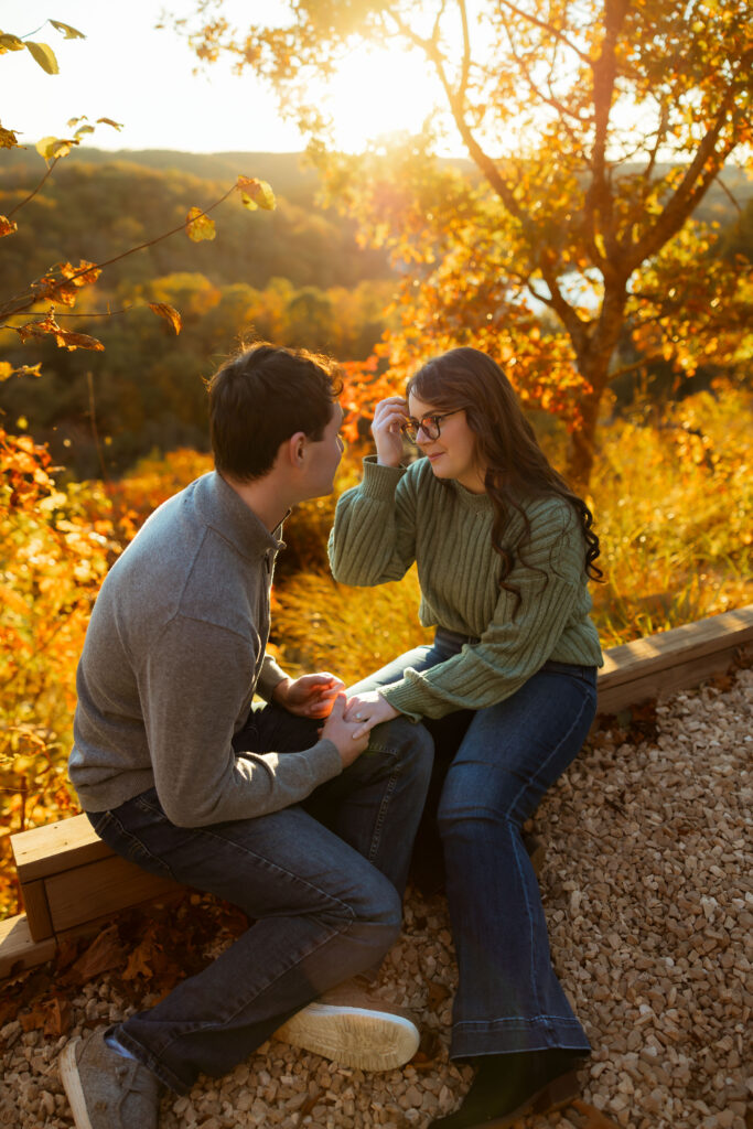 Engaged couple sharing a romantic moment among vibrant fall foliage at Ha Ha Tonka State Park in Missouri