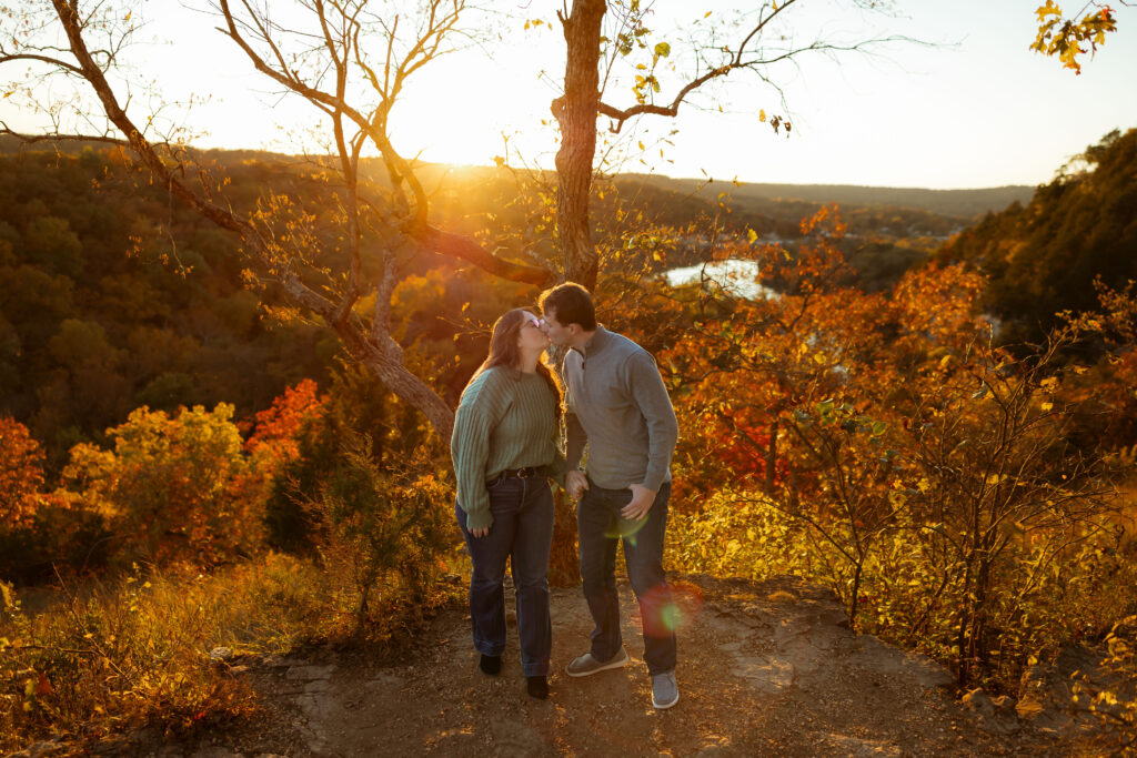 Engaged couple sharing a romantic moment among vibrant fall foliage at Ha Ha Tonka State Park in Missouri
