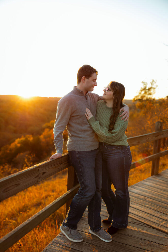 Engaged couple sharing a romantic moment among vibrant fall foliage at Ha Ha Tonka State Park in Missouri