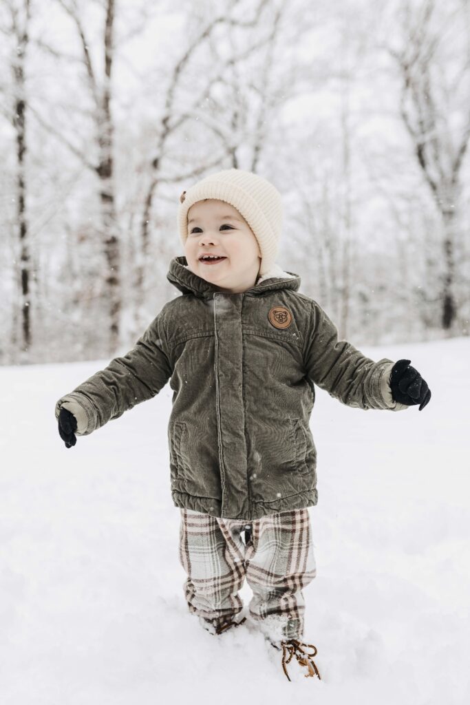 Documentary-style winter photo of a toddler experiencing snow for the first time