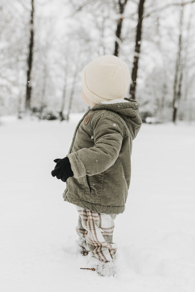 Documentary-style winter photo of a toddler experiencing snow for the first time