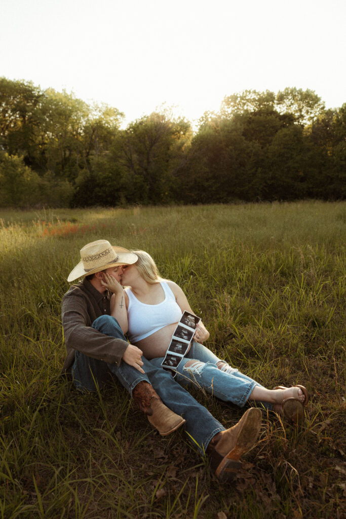 Expecting couple embracing during outdoor maternity session in Missouri with soft golden hour light and earthy documentary photography style.