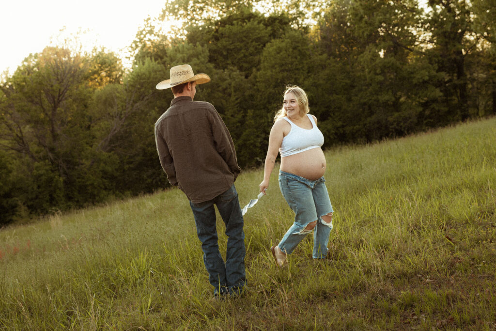 Outdoor maternity session in Missouri captured at golden hour in an open field with earthy tones and emotive film-inspired photography style.