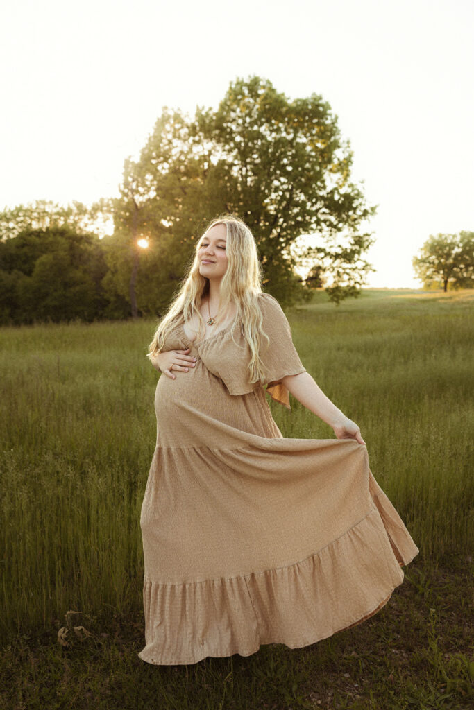 Outdoor maternity session in Missouri captured at golden hour in an open field with earthy tones and emotive film-inspired photography style.